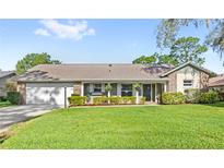 Charming single-story home with a well-manicured lawn, complemented by lush landscaping and a welcoming front porch at 315 Pickering Ct, Longwood, FL 32779