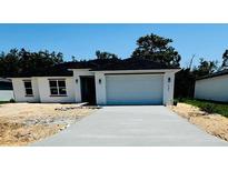 Charming single-story home with a white exterior, attached garage, and well-lit entryway at 506 St Johns Ct, Poinciana, FL 34759
