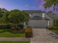 Charming two-story home showcasing a well-manicured lawn, mature tree, and attached two-car garage at 554 Queensbridge Dr, Lake Mary, FL 32746