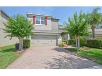 Two-story home with red shutters, two-car garage, brick paver driveway, and neatly landscaped front yard at 5908 Paxton Ct, Apopka, FL 32703