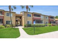 A well-maintained building exterior with lush green landscaping and palm trees on a sunny day at 648 Kenwick Cir # 102, Casselberry, FL 32707