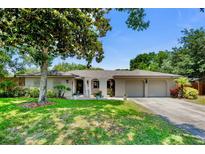 Charming single-story home featuring a well-manicured lawn, mature tree, and two-car garage at 8655 Shady Glen Dr, Orlando, FL 32819