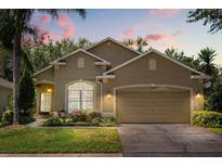 Charming single-story home featuring a two-car garage, well-manicured lawn, and colorful landscaping at 9644 Myrtle Creek Ln, Orlando, FL 32832