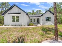 Charming white exterior with black trim, modern windows, and walkway to front door at 1394 Kettledrum Trl, Deltona, FL 32725