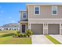 Charming two-story townhome featuring a two-car garage and well-manicured landscaping against a clear blue sky at 1401 Mirabella Cir, Davenport, FL 33897