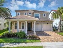 Beautiful two-story home with a two-car garage, classic columns, tile roof, and lush tropical landscaping at 15769 Shorebird Ln, Winter Garden, FL 34787