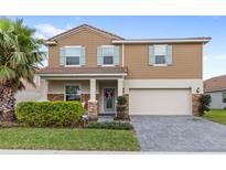 Charming two-story home with well-maintained landscaping, tan exterior and a paved driveway, featuring a two car garage at 1640 Oak Blossom Dr, Davenport, FL 33837