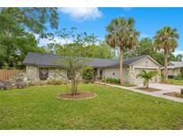 Charming single-story home featuring stone accents, a well-manicured lawn, and lush palm trees at 2901 Autumnwood Trl, Apopka, FL 32703