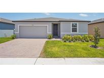 Charming one-story home with a brick driveway, gray exterior, and well-maintained lawn at 3210 Viceroy Ct, Poinciana, FL 34759