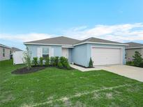 Charming, single-story home boasts a neatly landscaped yard, attached garage, and appealing curb appeal under a bright sky at 440 Patricia Alford Dr, Haines City, FL 33844