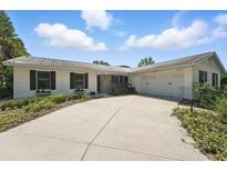 Charming single-story home with a tile roof, lush landscaping, and a spacious driveway leading to a two-car garage at 6327 Ridgeberry Dr, Orlando, FL 32819