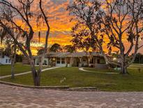 Charming home with pergola and beautiful landscaping, set against a vibrant sunset sky at 775 Bay Dr, New Smyrna Beach, FL 32168