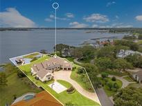 Stunning aerial view of a lakefront property with a private dock, basketball court, and beautifully landscaped grounds at 10845 Bayshore Dr, Windermere, FL 34786