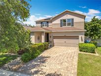 Two-story home showcasing a brick driveway, well-maintained landscaping, and a welcoming front entrance at 11868 Thatcher Ave, Orlando, FL 32836