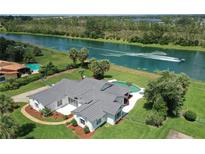 Stunning aerial view of a waterfront home with a pool and lush landscaping, featuring boaters enjoying the water at 12508 Lake Denise Blvd, Clermont, FL 34711