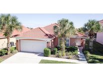 Charming single-story home with a red tile roof, tropical landscaping, and an attached two-car garage at 156 Carrera Ave, Davenport, FL 33897