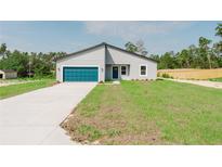 New construction home with a modern exterior, blue garage door, and freshly installed lawn at 17434 Sw 36Th Avenue Rd, Ocala, FL 34473
