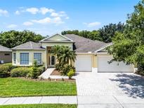 Charming single-story home with a well-manicured lawn, a three-car garage, and lush landscaping at 2026 Winding Oaks Dr, Orlando, FL 32825