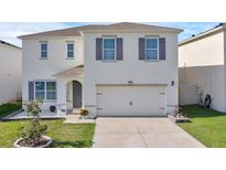 Two-story home featuring a well-manicured lawn and a spacious two-car garage, enhancing curb appeal at 269 Ludisia Loop, Davenport, FL 33837