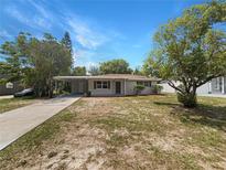 Charming single-story home featuring a carport, well-maintained lawn, and beautiful landscaping under a bright blue sky at 300 Avenue E Se, Winter Haven, FL 33880