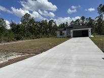 New construction home featuring a black roof and gutters, set on a verdant lawn at 3391 Orchid Dr, Indian Lake Estates, FL 33855