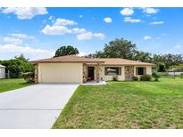 Charming single-story home featuring a two-car garage, stone accents, and a well-manicured lawn at 409 Jumper S Dr, Bushnell, FL 33513