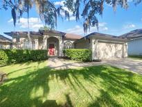 Charming single-Gathering home featuring lush landscaping, a two-car garage, and a classic red front door at 704 Pickfair Ter, Lake Mary, FL 32746
