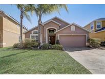 Charming home featuring a well-manicured lawn, mature palm trees, and an attached two-car garage at 927 Orange Cosmos Blvd, Davenport, FL 33837