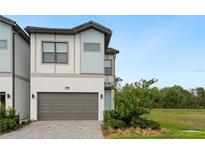Beautiful two-story home featuring a gray garage door, manicured lawn, and a contemporary design at 10251 Ebb Tide Ln, Orlando, FL 32821