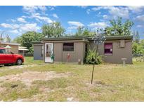 Single story home with a tan exterior and a red car parked in the front yard at 11509 Cameron St, Orlando, FL 32817