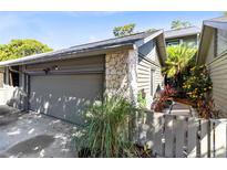 Attached garage featuring a stone accent wall and lush landscaping at 140 Deer Lake Cir, Ormond Beach, FL 32174