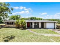 Charming single-story home with stone accents, a red front door and a well manicured lawn at 1508 Lake Mills Rd, Chuluota, FL 32766