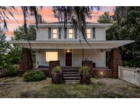 Charming two-story home with a brick porch and a neatly landscaped yard at sunset at 2418 W 1St St, Sanford, FL 32771