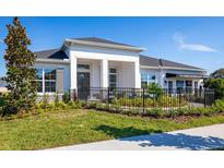 Charming home featuring a manicured lawn, dark roof, a black metal fence, and white columns at 2739 Ravencliffe Ter, Oviedo, FL 32765