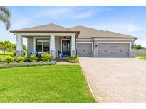 Beautiful single-story home with a three-car garage, well-manicured lawn, and a welcoming front porch seating area at 3630 Trimaran Dr, Orlando, FL 32820