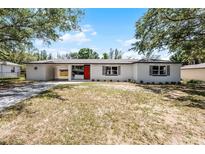 Charming one-story home with a covered carport, bright red door, and freshly painted white exterior at 410 W Seminole Ave, Eustis, FL 32726