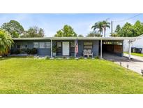 Lovely one-story home featuring an open carport, tidy lawn, and welcoming front porch at 5384 Barton Dr, Orlando, FL 32807