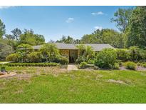 Charming single-story home with lush landscaping, mature trees, and stone accents at 98 Wisteria Dr, Longwood, FL 32779