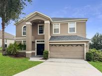Two-story home with a neutral color scheme, arched entryway, and an attached two-car garage at 12824 Cloverdale Ln, Clermont, FL 34711