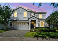Charming two-story home showcasing lush landscaping and a paver driveway at 1520 Mulligan Blvd, Davenport, FL 33896