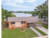 Inviting waterfront home featuring a well-maintained lawn and a convenient carport at 331 Greens End St, Orlando, FL 32810
