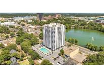 Stunning aerial view of high-rise condo featuring a pool, well-manicured landscaping, and beautiful lake views at 400 E Colonial Dr # 1609, Orlando, FL 32803