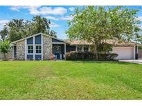Charming single-story home featuring stone accents, blue siding, mature trees and a lush green lawn at 704 Tangerine Ct, Winter Garden, FL 34787
