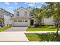 Two-story home featuring a manicured lawn, beautiful landscaping, and an attached two-car garage at 8822 Interlocking Ct, Davenport, FL 33896