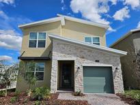 Charming home features a stone facade, green garage door, and meticulously manicured landscaping at 949 Leader St, Davenport, FL 33896