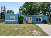 Charming blue single-story home with a bright yellow front door and a well-maintained lawn at 11520 Churchill St, Orlando, FL 32817