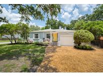 Charming single-story home features a brick driveway, yellow front door, and well-manicured landscaping at 1225 Golfview St, Orlando, FL 32804