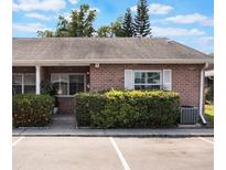 Charming brick condo featuring a well-maintained lawn and assigned parking spaces at 1230 Americana Pl, Orlando, FL 32807