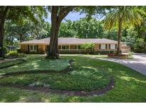 Stunning brick home featuring lush landscaping, mature trees, and a circular driveway at 2009 Woody Dr, Windermere, FL 34786