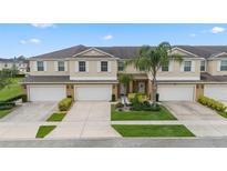 Beige two-story townhome featuring a well-maintained front yard, a driveway, and a one-car garage at 3018 Bargate St, Orlando, FL 32824